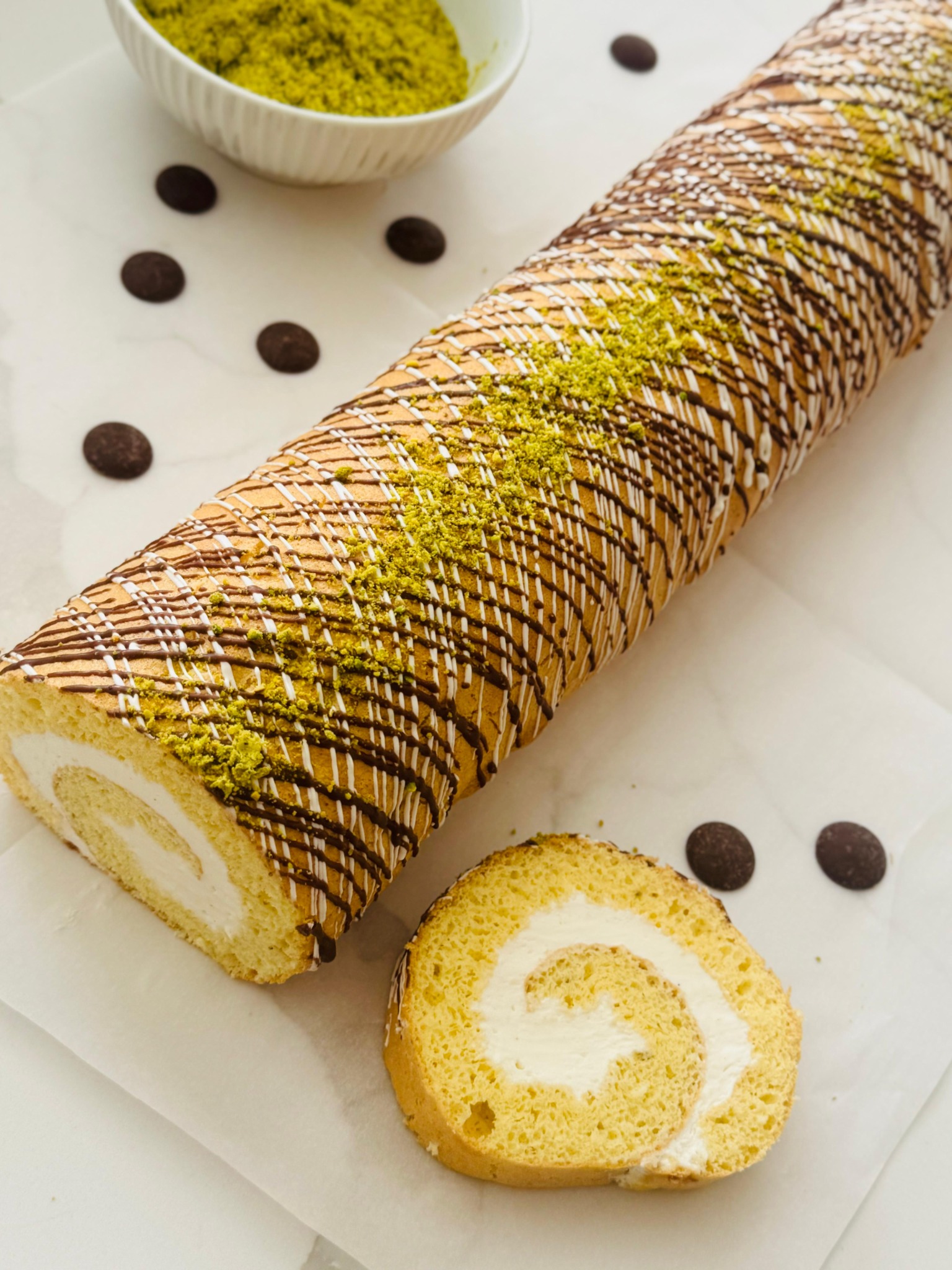Cream-filled cake roll decorated with chocolate and pistachio